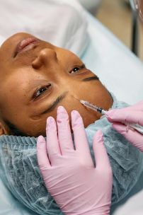 Close-up of a cosmetic professional administering a Botox injection on a patient's forehead in a clinic.
