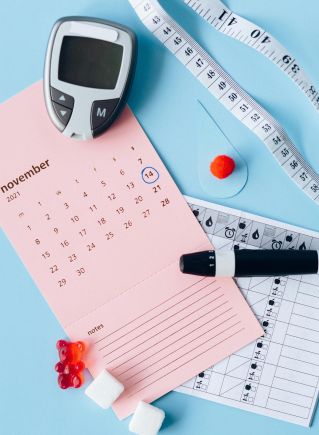 Flat lay of diabetes awareness tools on a blue backdrop with calendar.